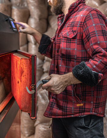 A man in a room with a solid fuel boiler, working on biofuel, economical heating.